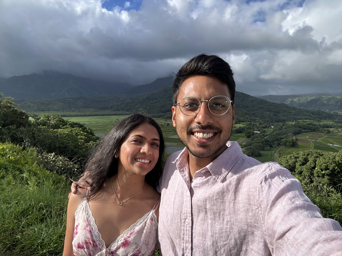 Aditi and Vedant outdoors with green hills behind them