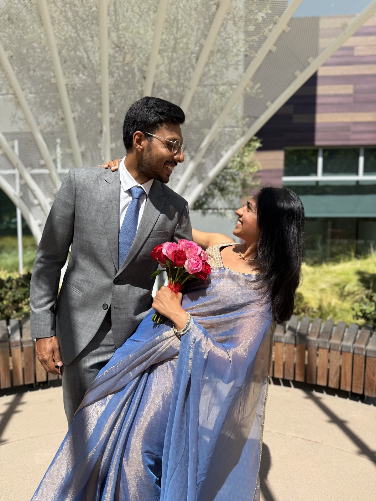 Aditi and Vedant dressed up together, holding a bouquet of roses